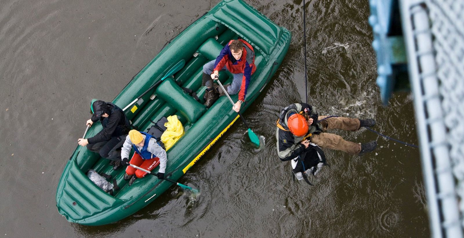 Záchrana z raftu pod mostem, záchranář slaňuje k lodi